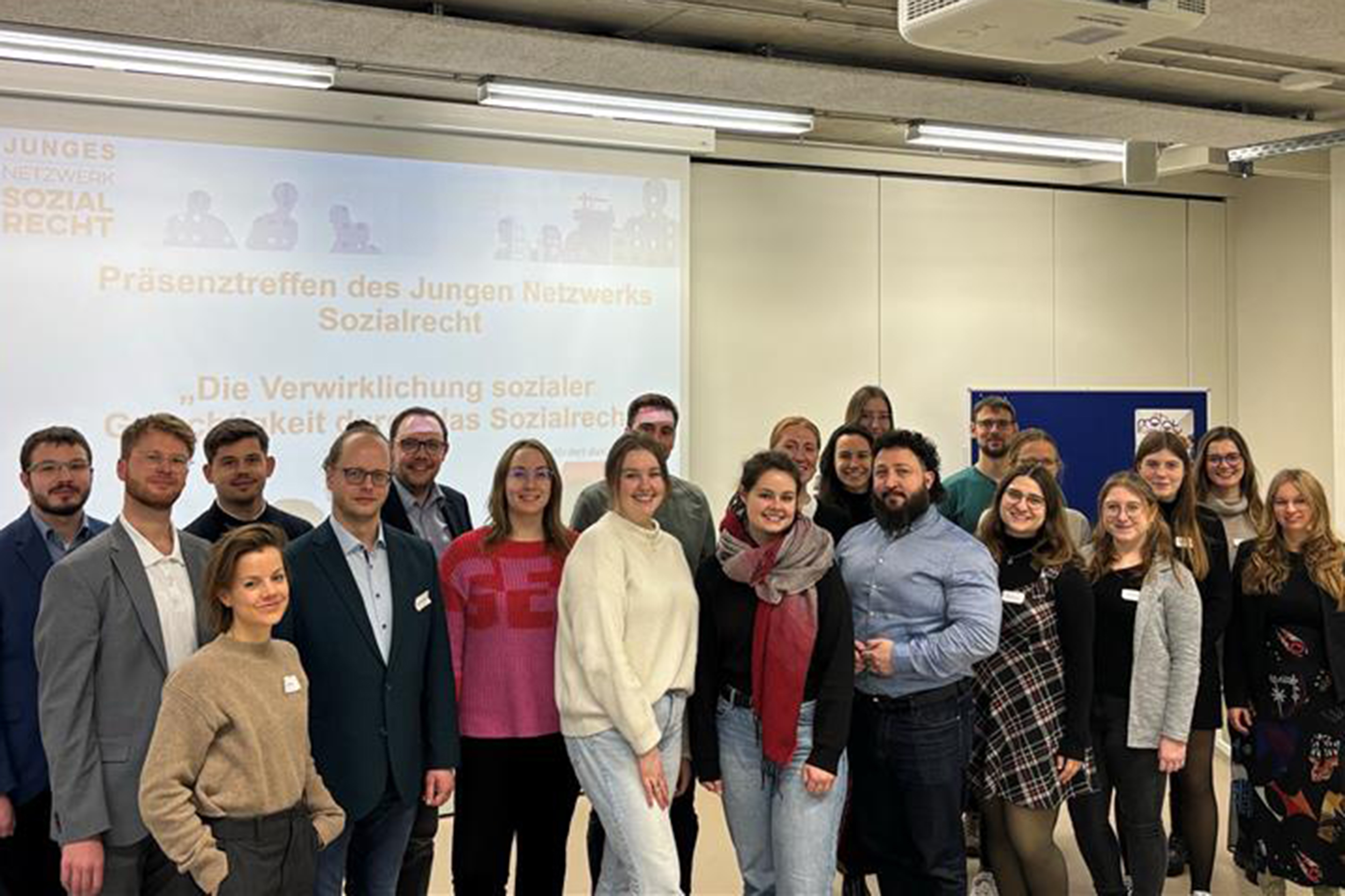 die Mitglieder des Jungen Netzwerks stehen für ein Gruppenfoto vor einer Leinwand